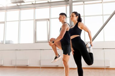 beautiful athletic couple in sportswear warm up in the gym in the morning, fitness girl and coach man go in for sports in training in bright room