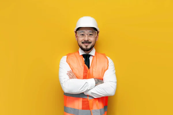 asian builder engineer in uniform on yellow isolated background, male korean man in hard hat and work vest worker architect