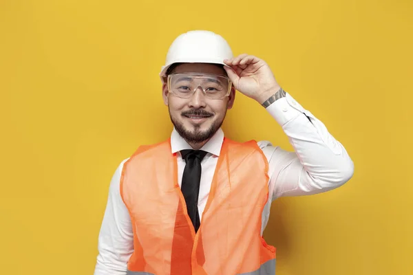 asian builder engineer in uniform on yellow isolated background, male korean man in hard hat and work vest worker architect
