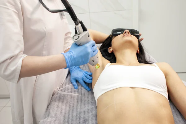 woman patient on armpit hair removal procedure in cosmetology clinic, cosmetologist doctor removes hair from armpits with alexandrite laser