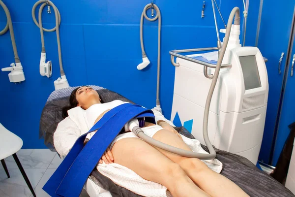 coolsculpting procedure in cosmetology clinic, the girl patient lies on the couch connected to the machine to remove fat from the abdomen
