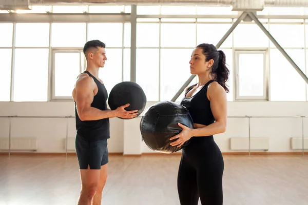 stock image young beautiful athletic couple in sportswear at crossfit training with ball in the fitness room, woman and man together at fitness training go in for sports and do endurance exercise