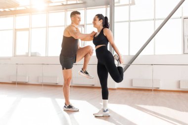 beautiful athletic couple in sportswear warm up in the gym in the morning, fitness girl and coach man go in for sports in training in bright room