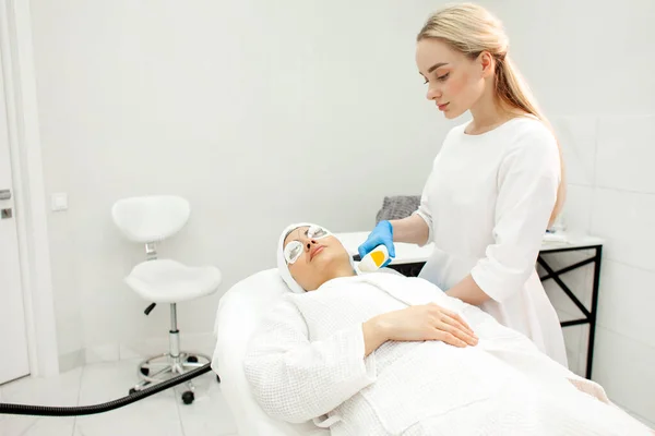 cosmetologist doctor makes laser face cleaning to woman patient in cosmetology clinic, professional cosmetology concept, modern cosmetology