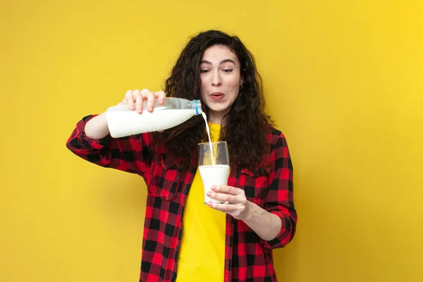 Genç Neşeli Kıvırcık Kız Sütü Şişeden Bardağa Doldurup Sarı Arka — Stok fotoğraf