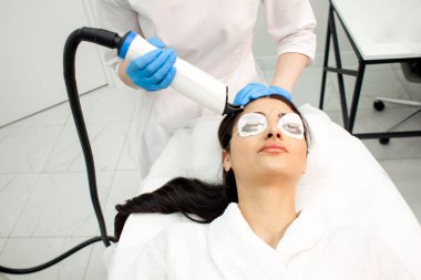procedure of laser stimulation of hair growth, doctor cosmetologist makes a procedure against hair loss in a cosmetology clinic with modern equipment