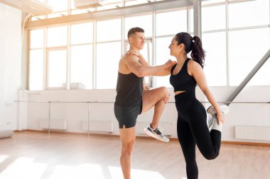 beautiful athletic couple in sportswear warm up in the gym in the morning, fitness girl and coach man go in for sports in training in bright room