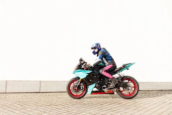 プロの保護機器やヘルメットに男のオートバイは白い壁に対して高速オートバイに乗る 服にプロのオートバイに乗る自転車 — ストック写真