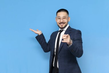 Hey sen, takım elbiseli ve gözlüklü başarılı Asyalı işadamı mavi arka planda seni işaret ediyor, iş elbiseli Koreli girişimci fotokopi alanında elini gösteriyor.