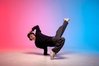 Siyah elbiseli genç dansçı neon ışıkta dans ediyor, adam kırmızı mavi kulüpte hip hop hareketi yapıyor.