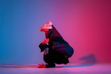 Siyah elbiseli genç dansçı neon ışıkta dans ediyor, adam kırmızı mavi kulüpte hip hop hareketi yapıyor.