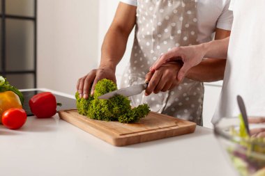 Çağdaş mutfakta sebze ve sebze hazırlayan çok ırklı genç bir çift. Önlüklü Afro-Amerikan bir adam. Yeşillik kesiyor, karısı yardım ediyor ve kocasına yemek yapmayı öğretiyor.