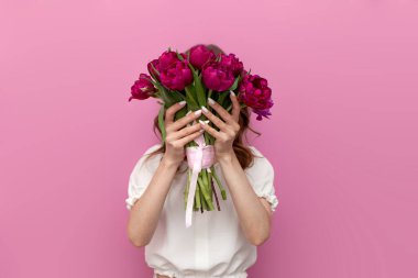 Kadın pembe arka planda bir buket pembe lale tutuyor, bayram için çiçekli kız, 8 Mart ve çiçekçi konsepti