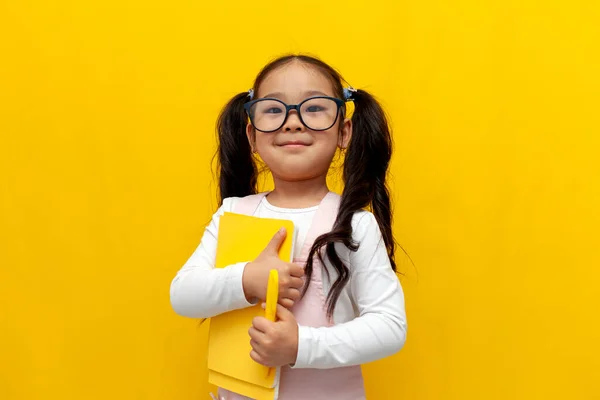 Niña Asiática Con Gafas Sosteniendo Libros Sonriendo Sobre Amarillo Aislado — Foto de Stock