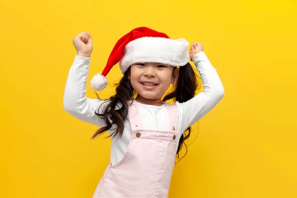 Noel Baba Şapkalı Küçük Asyalı Kız Sarı Arka Plandaki Zaferle — Stok fotoğraf