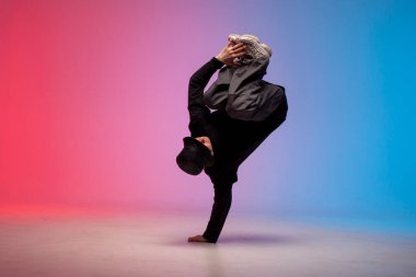 Siyah elbiseli genç dansçı neon ışıkta dans ediyor, adam kırmızı mavi kulüpte hip hop hareketi yapıyor.