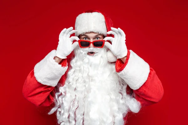 Zszokowany Mikołaj Czerwonych Okularach Patrzy Aparat Zaskoczeniu Jest Zdumiony Kolorowym — Zdjęcie stockowe