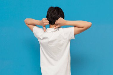 Genç çocuk arkası dönük durur ve ellerini mavi izole arka planda gösterir. Beyaz tişörtlü çocuk sırtında ve dikiz aynasındaki boşluğu gösterir.