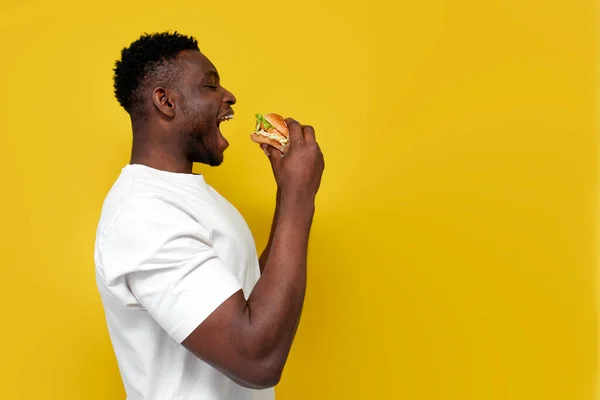 Афроамериканець Білій Футболці Тримає Великий Бургер Відкритим Ротом Хлопець Їсть — стокове фото