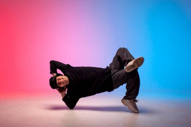 Genç hiphop sanatçısı Neon Club ışıklandırmasında break dans yapıyor ve akrobatik numaralar yapıyor. Erkek dansçı akrobatik pozlar veriyor.