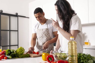 Çağdaş mutfakta sebze ve sebze hazırlayan çok ırklı genç bir çift. Önlüklü Afro-Amerikan bir adam. Yeşillik kesiyor, karısı yardım ediyor ve kocasına yemek yapmayı öğretiyor.