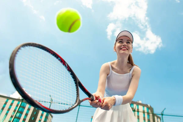 白いユニフォームの女子テニス選手がテニスコートでラケットを持ち 女子アスリートが屋外で空に向かってテニスをしてボールを打つ — ストック写真