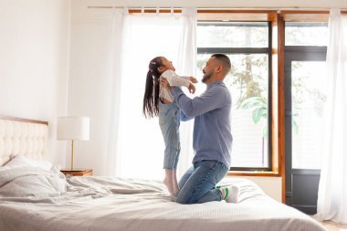 Asyalı baba evde kızıyla oynuyor, Koreli kız babasının kollarında gülüyor, baba sevgisi kavramı.