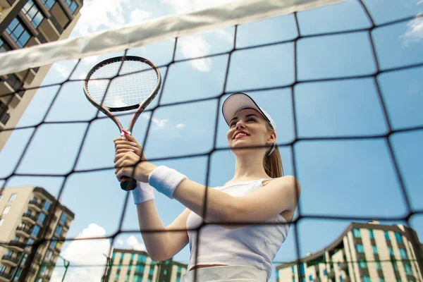 白い制服の女子テニス選手はテニスコートでラケットを持っています女性選手は空に対して屋外でテニスをします — ストック写真