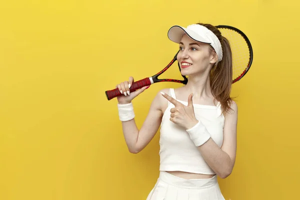 Tenisistka Dziewczyna Odzieży Sportowej Trzyma Rakietę Tenisową Wskazuje Bok Żółtym — Zdjęcie stockowe