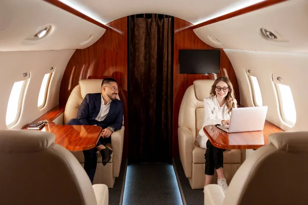 business people are flying in private luxury plane, asian businessman in suit and woman manager are sitting in the plane and discussing the workflow