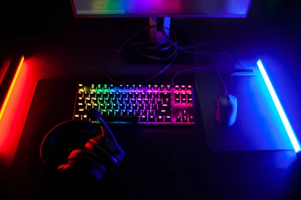 ゲーマーの職場 ネオン照明のコンピュータクラブで選手のデバイス ヘッドフォン キーボードやモニターをスポーツ — ストック写真
