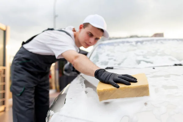 穿制服的年轻人洗车工人用海绵洗车 穿工作服的人在室外洗车 — 图库照片