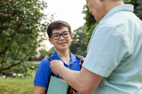 亚洲的老爸爸和儿子一起上学 带着书 韩国的男孩背着背包和眼镜 夏天和老爸爸一起上学 爷爷照顾孙子 — 图库照片