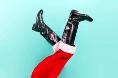 Noel Baba bacakları mavi izole edilmiş arka planda, siyah botlar ve kırmızı Noel Baba pantolonları ters duruyor, yeni yıl ve noel konsepti