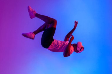 Sanal gerçeklik gözlüklü Afro-Amerikan bir adam havada süzülüyor ve neon ışıklarıyla havaya düşüyor, adam VR gözlükleriyle uçuyor, fantezi ve hayal gücü kavramı