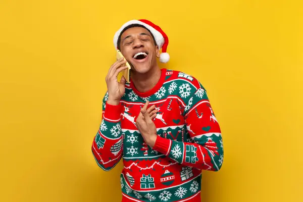 모자에 아프리카계 미국인 남자는 노란색 배경에 전화에 이야기 스웨터에 전화에 — 스톡 사진