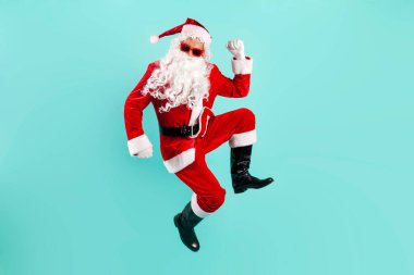 Noel Baba kılığında, pantolon askısı takmış genç bir adam mavi arka planda zıplıyor ve uçuyor. Noel Baba acele ediyor ve yeni yıl ve yeni yıl için koşuyor.