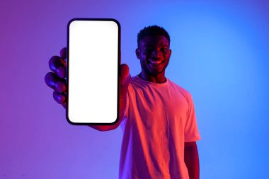 Afro-Amerikan adam boş akıllı telefon ekranını neon ışıkla gösteriyor, fotokopi alanının reklamını yapıyor ve gülümsüyor.