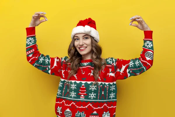 Mädchen Weihnachtspullover Und Weihnachtsmannmütze Hält Leere Hände Auf Gelbem Hintergrund — Stockfoto