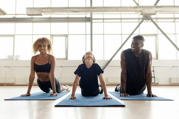 african american young family do yoga and sit on mat and meditate together, father mom and son on fitness training sitting in lotus position