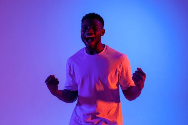 Afrikalı Amerikalı bağırıyor ve neon ışıkta zaferi kutluyor. Kazanan adam başarı ve iyi şanslar diliyor.