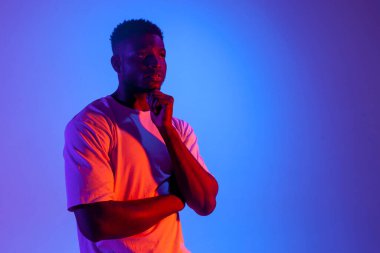 Düşünceli Afrikalı Amerikalı adam neon ışıkta düşünüyor ve hayal kuruyor, kafası karışmış adam plan yapıyor ve düşünüyor.