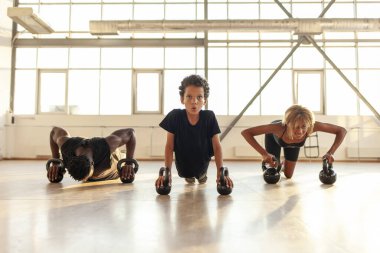 Spor giyim ve spor salonunda spor yapan Afro-Amerikan ailesi, ebeveynleri ile birlikte spor salonunda şınav çeken çocuk.