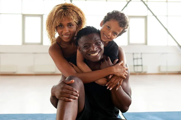 happy african american young family hugging and smiling in the gym, mom dad and son love together, 9 year old boy with parents