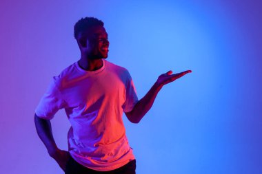 Afro-Amerikan adam neon ışıkta ellerini yana gösteriyor, adam gülümsüyor ve uzay fotokopisi çekiyor.