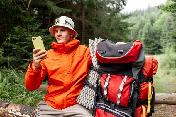 Turista Masculino Com Mochila Equipamento Caminhadas Senta Floresta Usa Smartphone — Fotografia de Stock