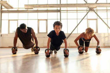 Spor giyim ve spor salonunda spor yapan Afro-Amerikan ailesi, ebeveynleri ile birlikte spor salonunda şınav çeken çocuk.