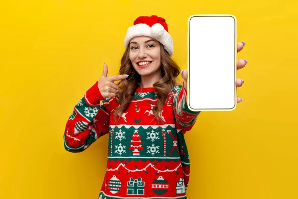 Dívka Vánoční Svetr Santa Claus Klobouk Ukazuje Prázdné Smartphone Obrazovka — Stock fotografie