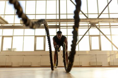 Afrika kökenli Amerikalı atletizm sporcusu spor salonunda antrenman yapıyor ve halatları sallıyor, sporcu spor yapıyor ve spor yapıyor.