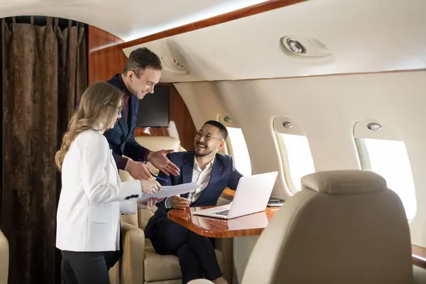 group of people at meeting fly in private jet and discuss business deal, the boss and colleagues in the plane communicate and work with documents and laptop